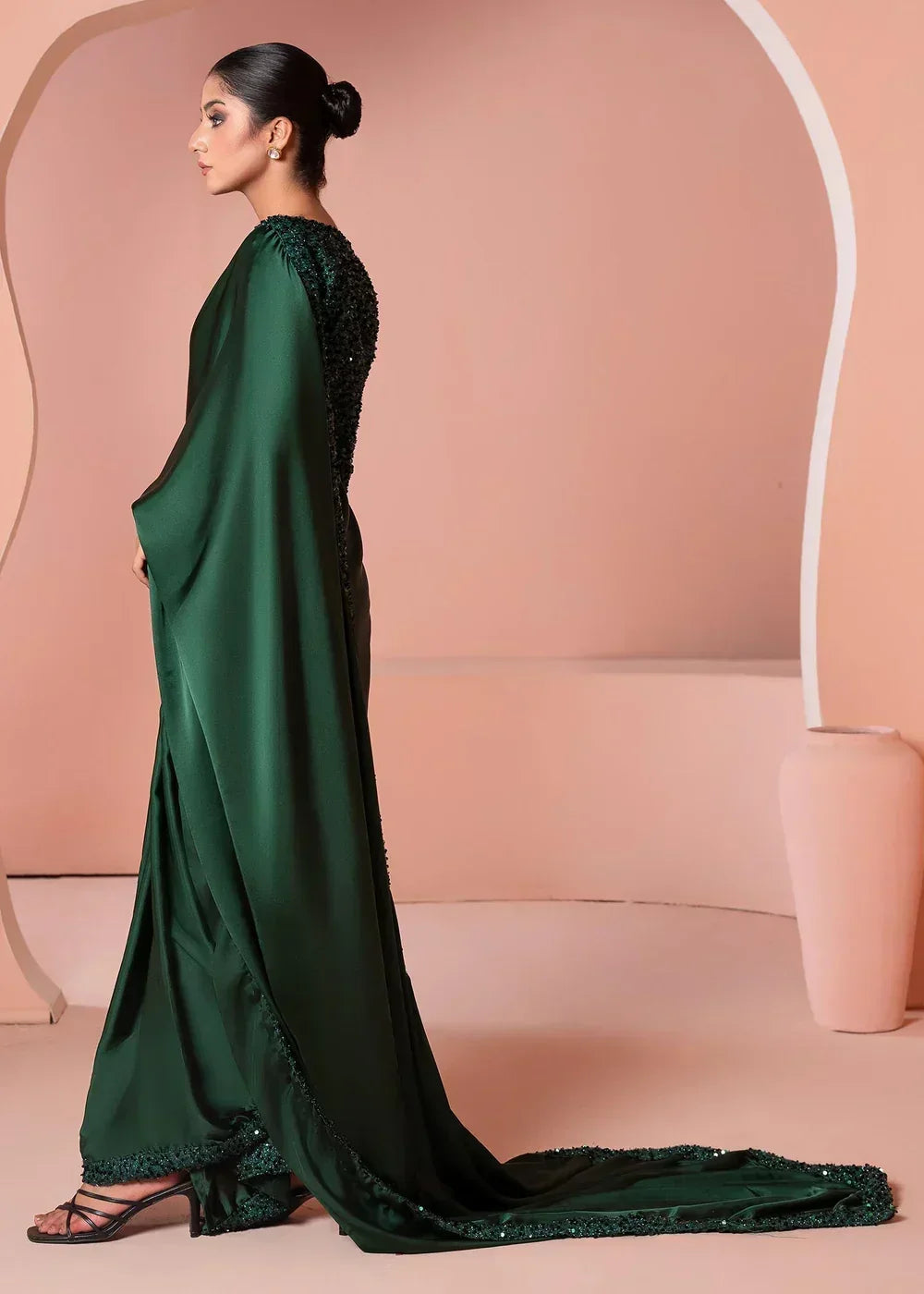 Woman modeling elegant dark green embroidered saree with trailing hem in modern studio