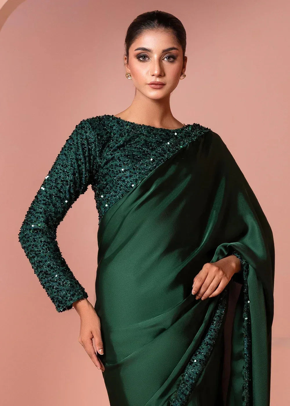 Woman wearing an elegant dark green sequin saree with long sleeves, posing indoors