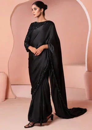 Woman wearing elegant black saree with subtle embellishments in a minimal studio setting