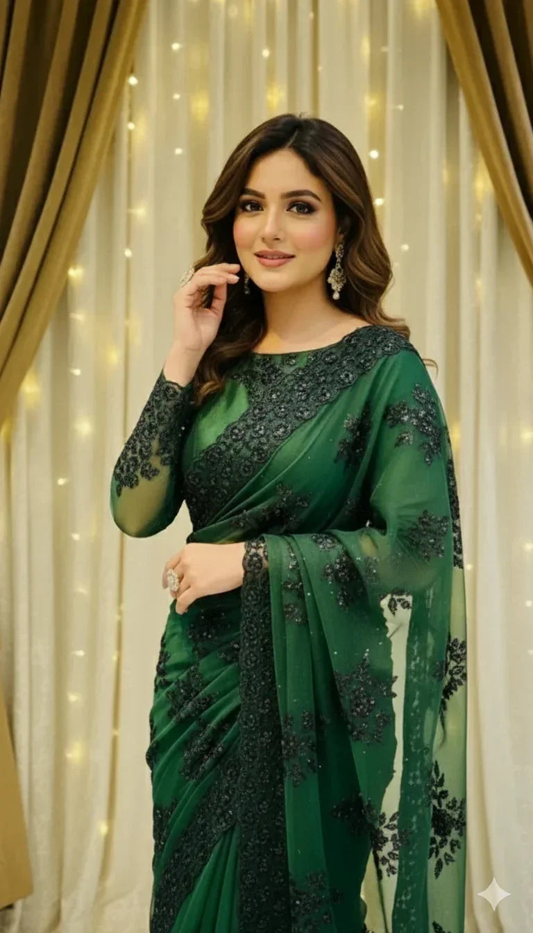 Woman in elegant green embroidered saree posing indoors with curtain and fairy light backdrop