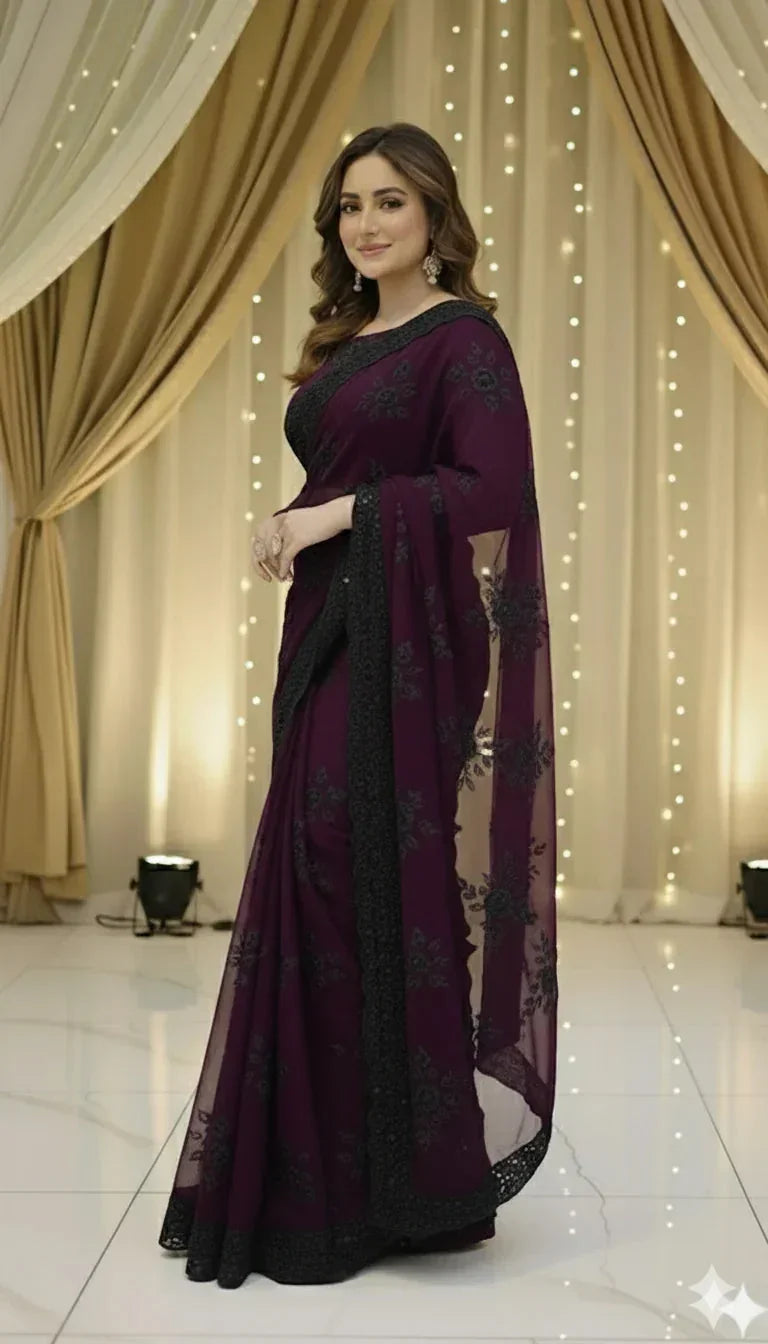 Woman in elegant plum saree with black floral embroidery at Sareeium jan event, festive lights backdrop
