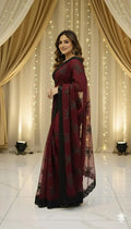 Woman in maroon saree with black floral accents, posing at Sareeium jan event with elegant drapes