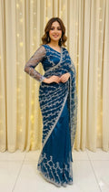 Woman in blue embroidered saree with sheer sleeves, elegant backdrop, Sareeium jan fashion