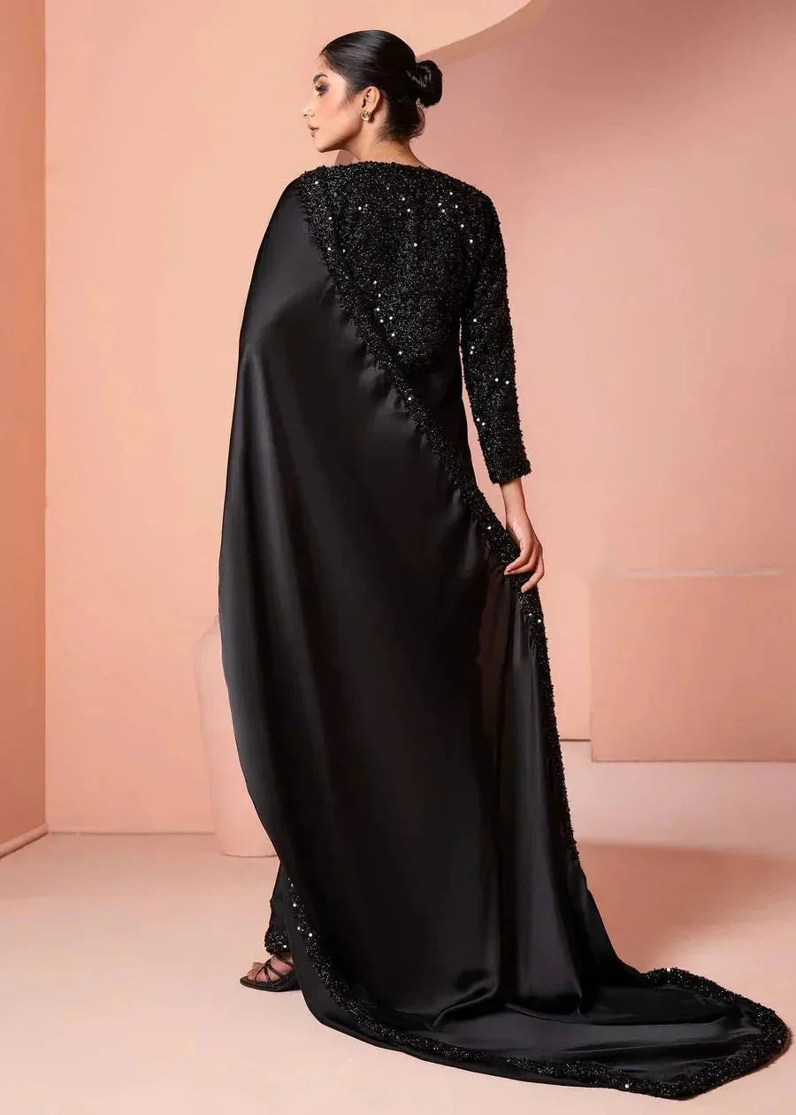 Woman wearing elegant black sequin saree with satin drape in modern studio setting