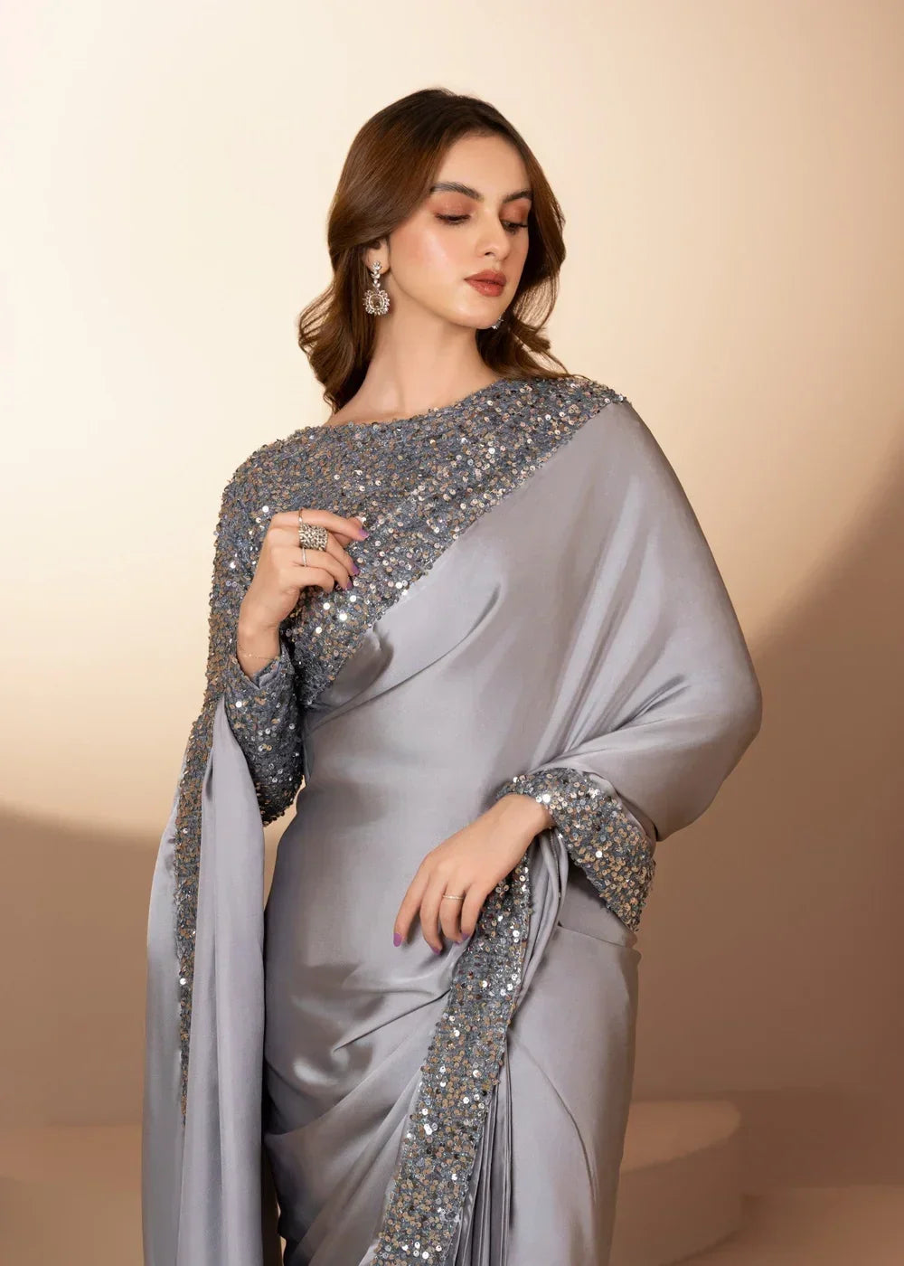 Woman in elegant silver sequin embellished saree with matching jewelry, studio background