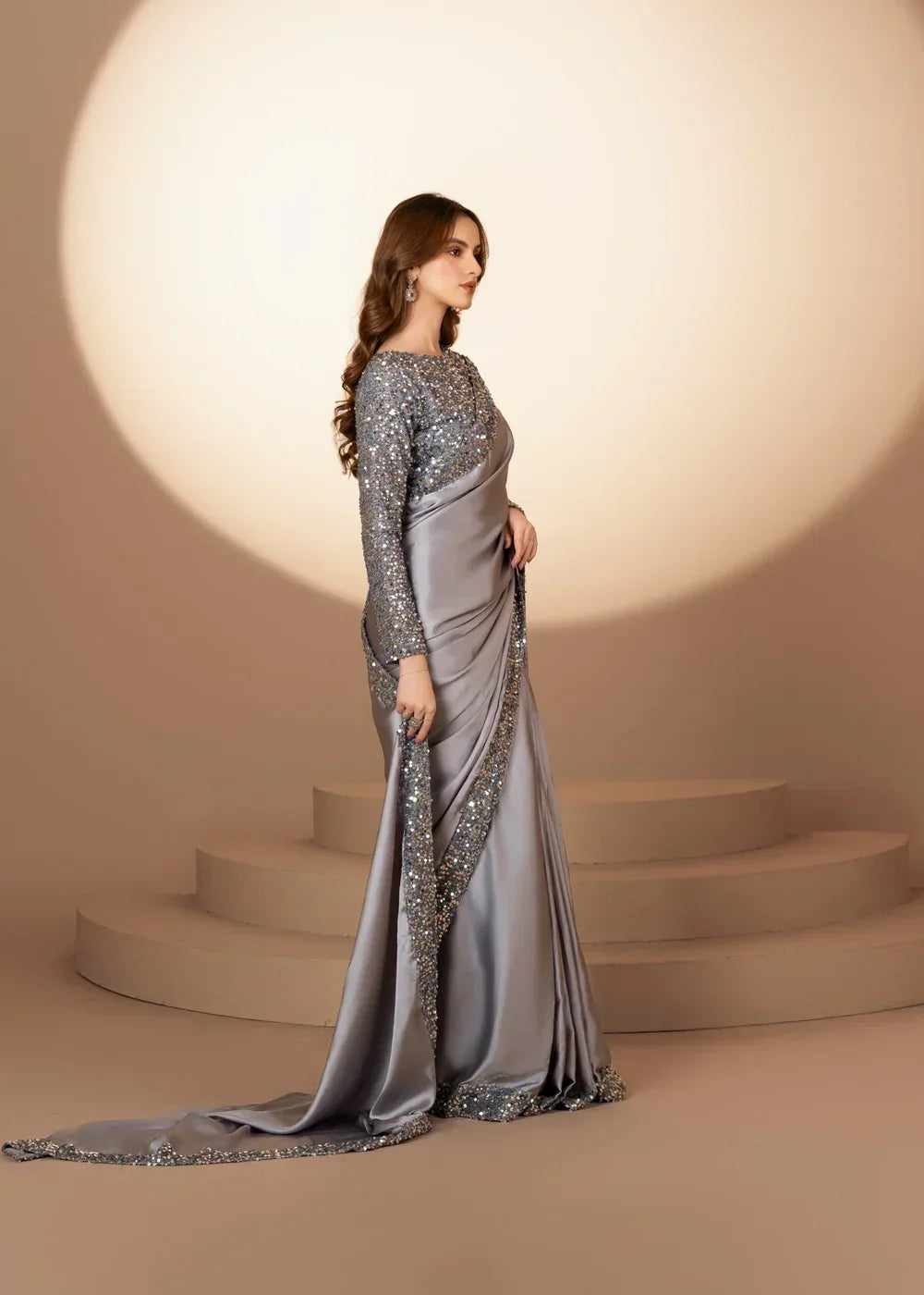 Woman in elegant silver sequin saree, stylish evening dress, standing on steps